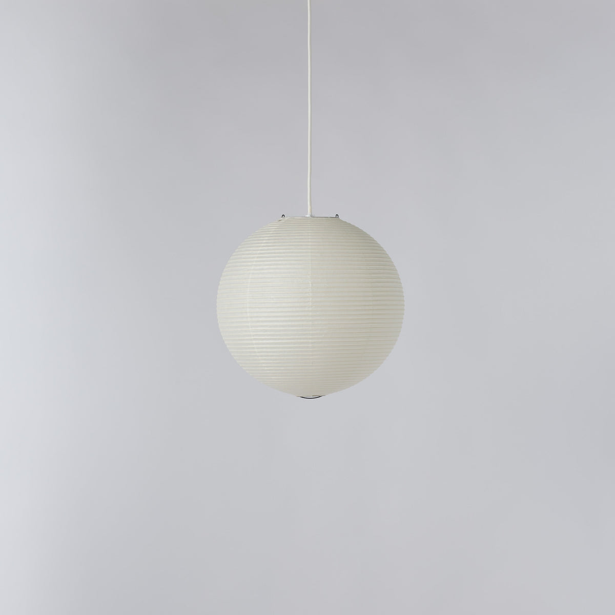 A spherical pendant light with a ribbed, pleated paper or fabric shade in an off-white color, suspended by a thin white cord against a plain light gray background.