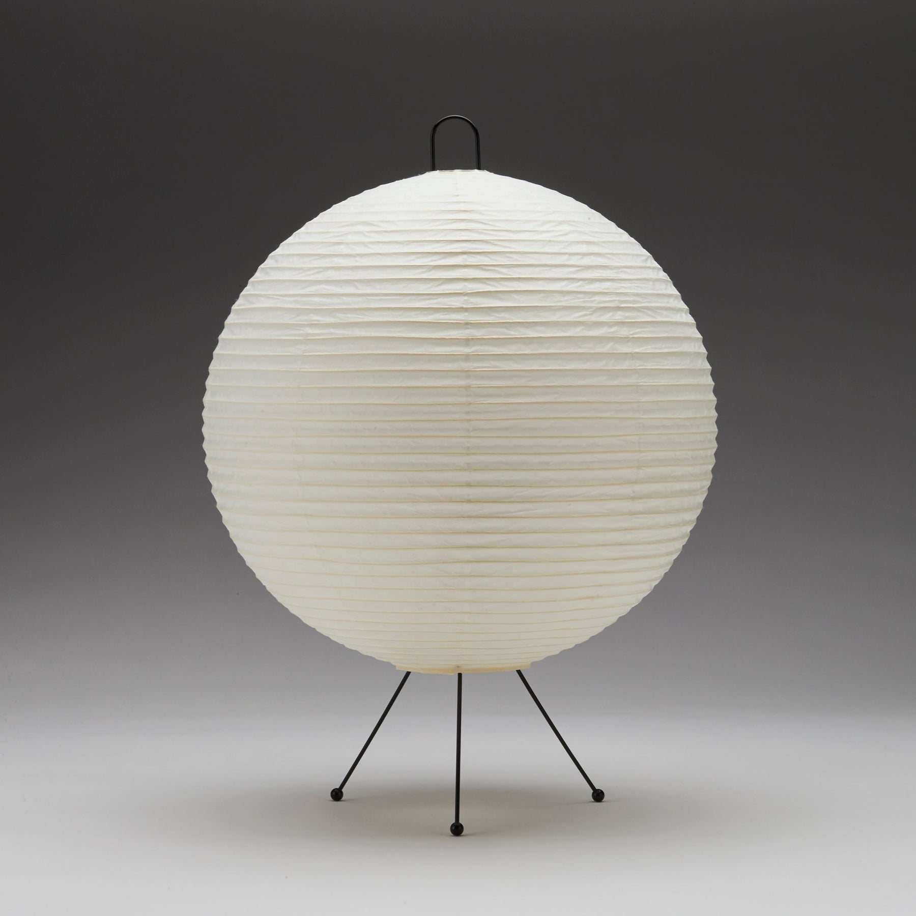 Spherical lamp with a textured white surface on a black stand against a gray background