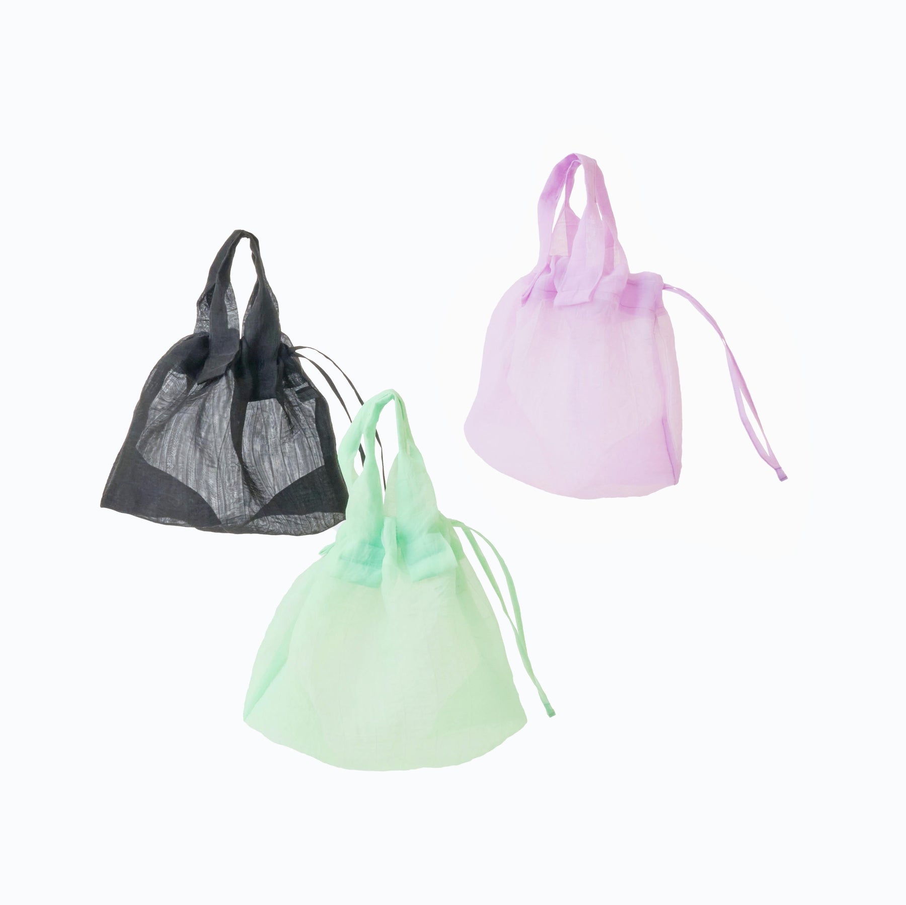 Three drawstring bags in black, green, and pink on a white background