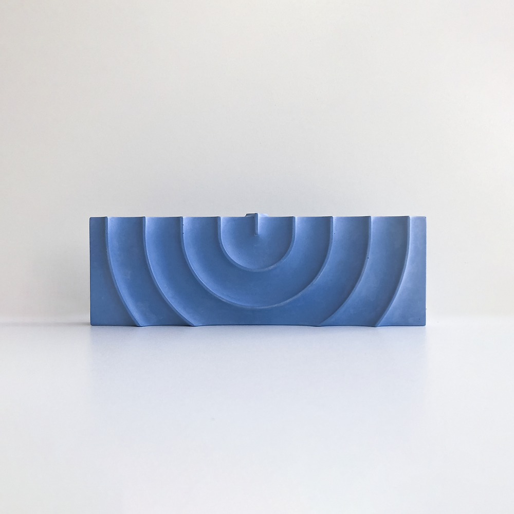 Logifaces, a geometric puzzle made of concrete triangular prisms, arranged in various configurations to form a continuous surface. The minimalist design encourages creative problem-solving and spatial thinking