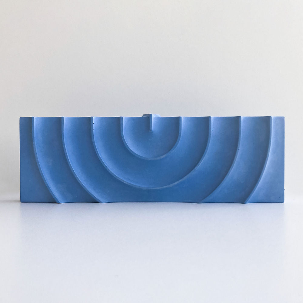 Logifaces, a geometric puzzle made of concrete triangular prisms, arranged in various configurations to form a continuous surface. The minimalist design encourages creative problem-solving and spatial thinking