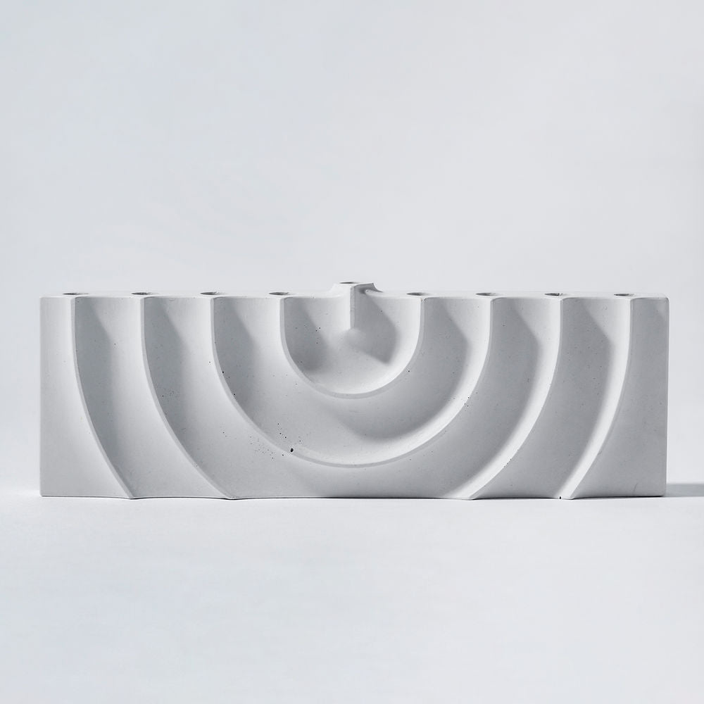 Logifaces, a geometric puzzle made of concrete triangular prisms, arranged in various configurations to form a continuous surface. The minimalist design encourages creative problem-solving and spatial thinking