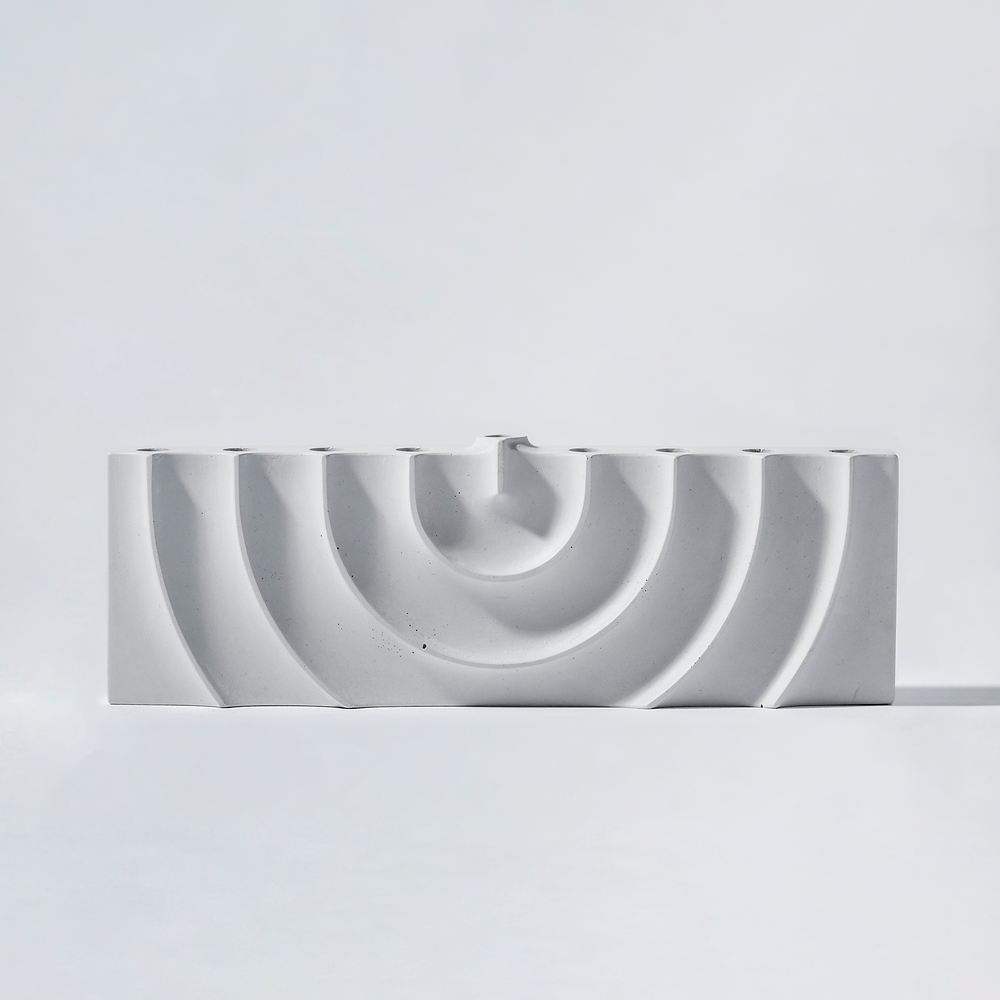Logifaces, a geometric puzzle made of concrete triangular prisms, arranged in various configurations to form a continuous surface. The minimalist design encourages creative problem-solving and spatial thinking