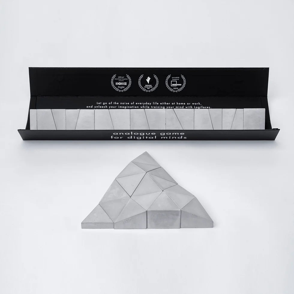 Logifaces, a geometric puzzle made of concrete triangular prisms, arranged in various configurations to form a continuous surface. The minimalist design encourages creative problem-solving and spatial thinking