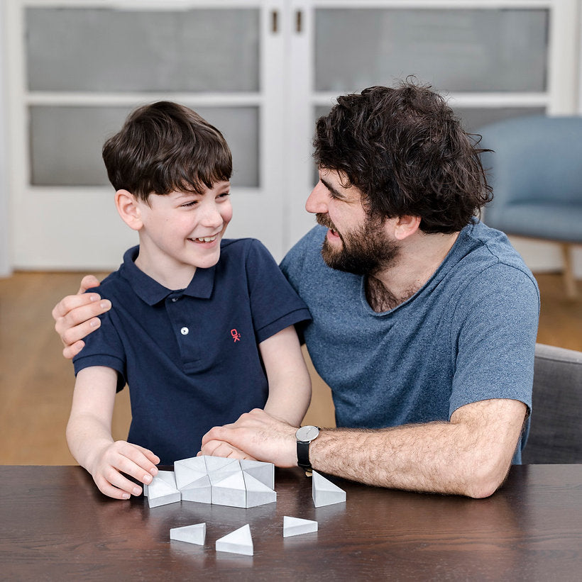 Logifaces, a geometric puzzle made of concrete triangular prisms, arranged in various configurations to form a continuous surface. The minimalist design encourages creative problem-solving and spatial thinking