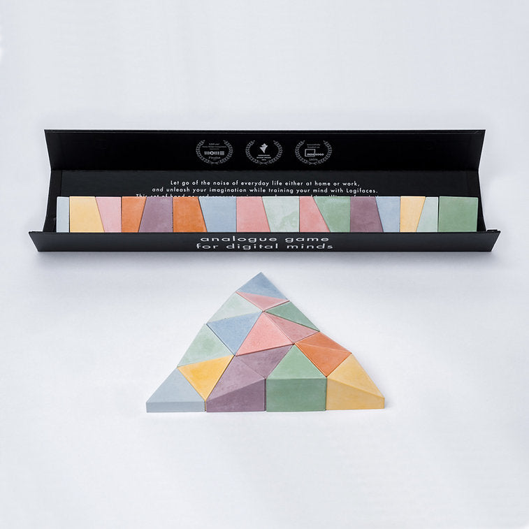 Logifaces, a geometric puzzle made of concrete triangular prisms, arranged in various configurations to form a continuous surface. The minimalist design encourages creative problem-solving and spatial thinking