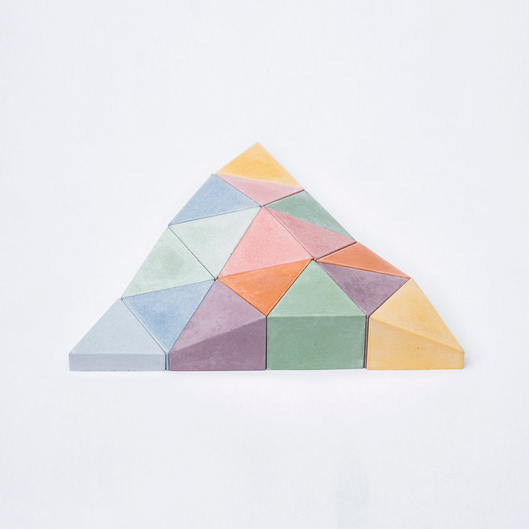 Logifaces, a geometric puzzle made of concrete triangular prisms, arranged in various configurations to form a continuous surface. The minimalist design encourages creative problem-solving and spatial thinking