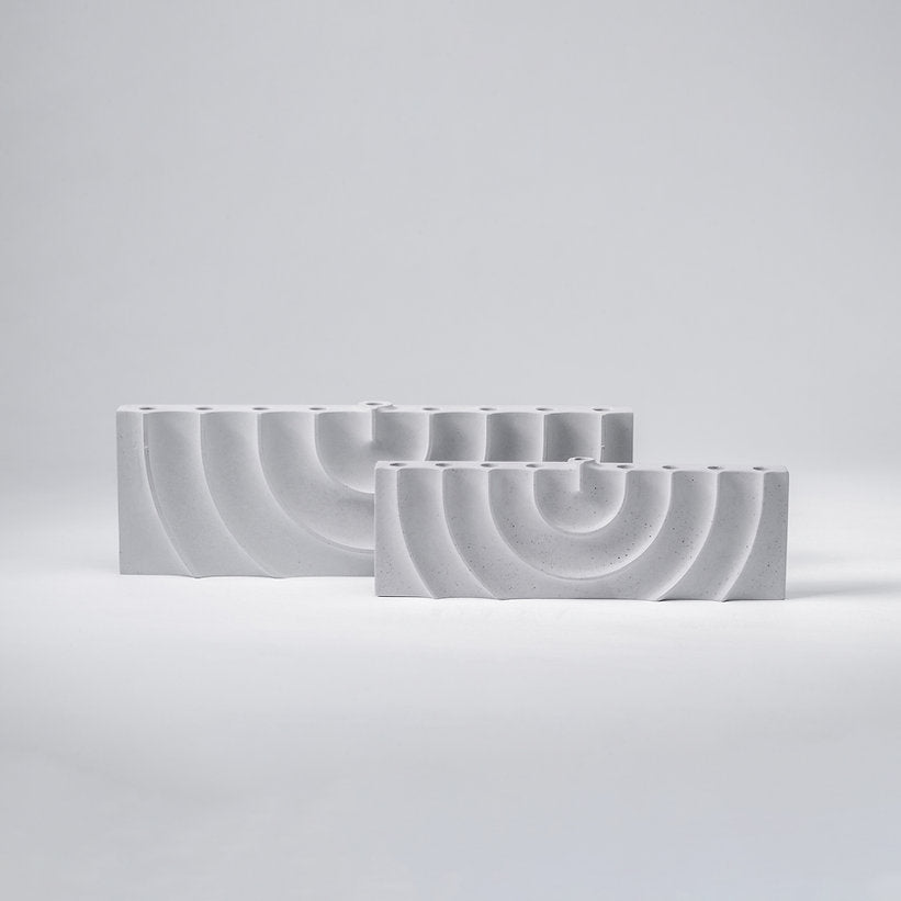 Logifaces, a geometric puzzle made of concrete triangular prisms, arranged in various configurations to form a continuous surface. The minimalist design encourages creative problem-solving and spatial thinking