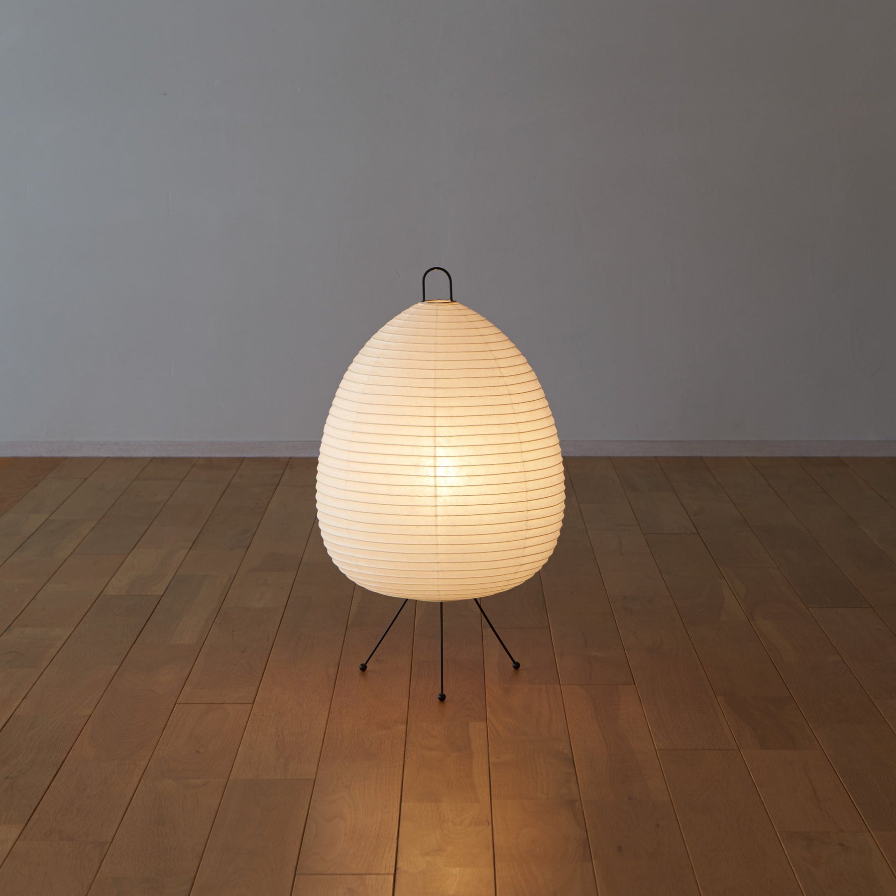 Paper lamp on a wooden floor with a plain wall background