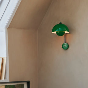 Green wall-mounted lamp on a beige wall with a window in the background
