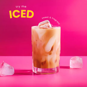 Glass of iced coffee with ice cubes on a pink background, text 'try me ICED sweet & fragrant'.