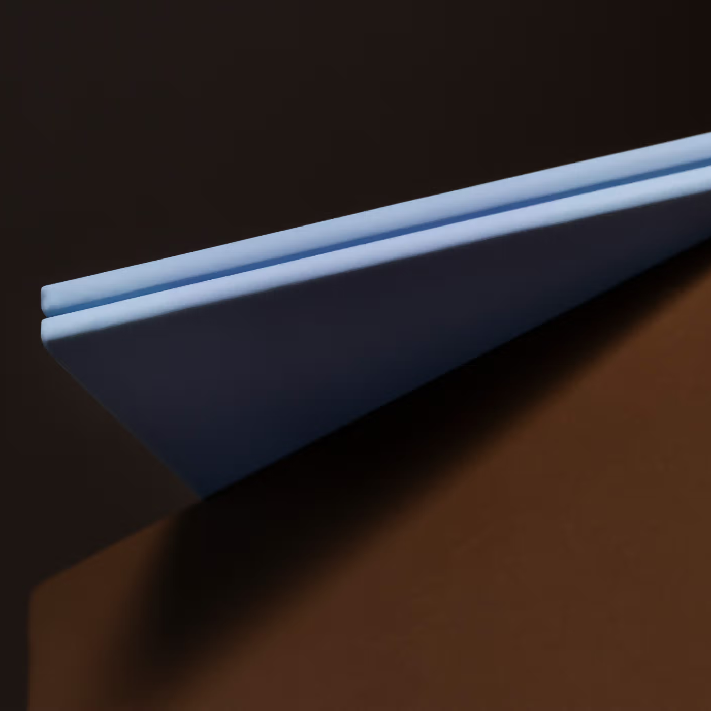 Blue plastic strip on a dark brown surface with a black background