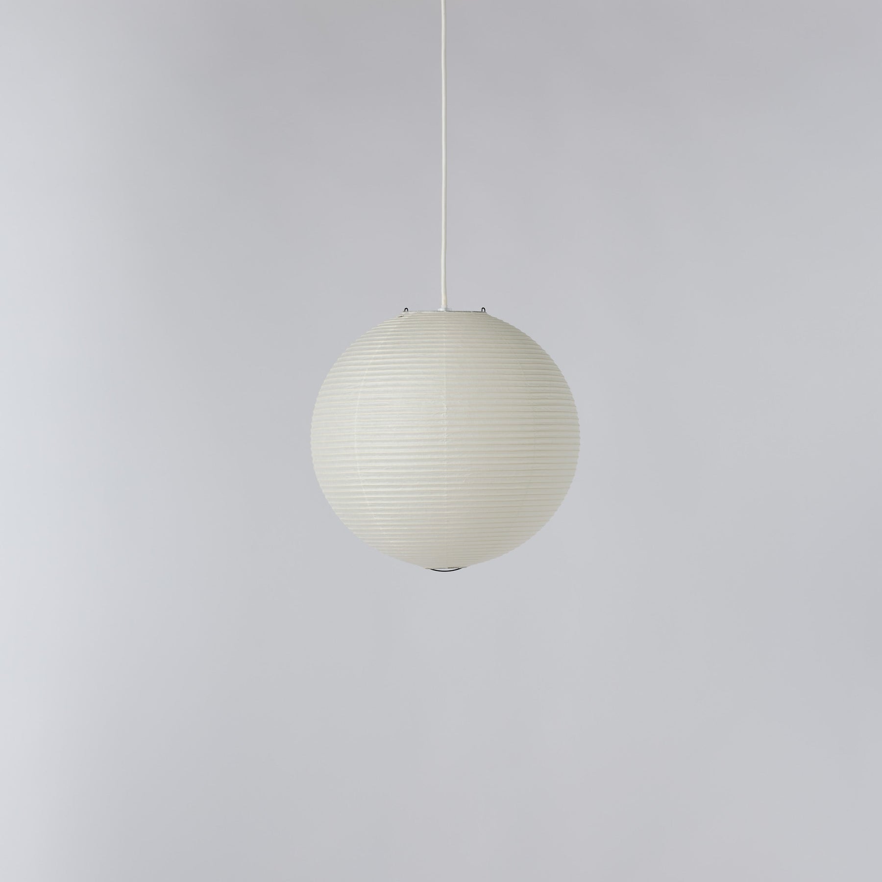 A spherical pendant light with a ribbed, pleated paper or fabric shade in an off-white color, suspended by a thin white cord against a plain light gray background.