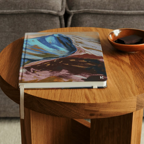 Wooden side table with a notebook and bowl against a gray sofa background