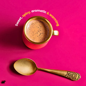 Red cup of coffee with gold spoon on a pink background