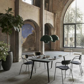 Modern dining area with a large table and chairs in a spacious room with high ceilings and large windows.