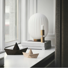 Two wooden boats on a surface with a modern lamp in the background.