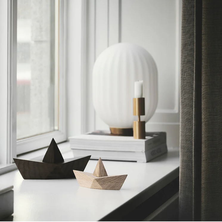Two wooden boats on a surface with a modern lamp in the background.