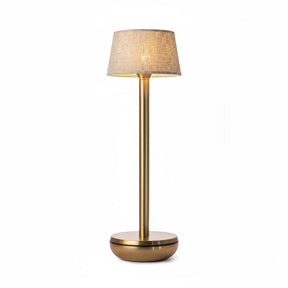A modern table lamp with a warm brass-finished metal stand and a textured beige fabric drum shade, shown illuminated against a plain white background.