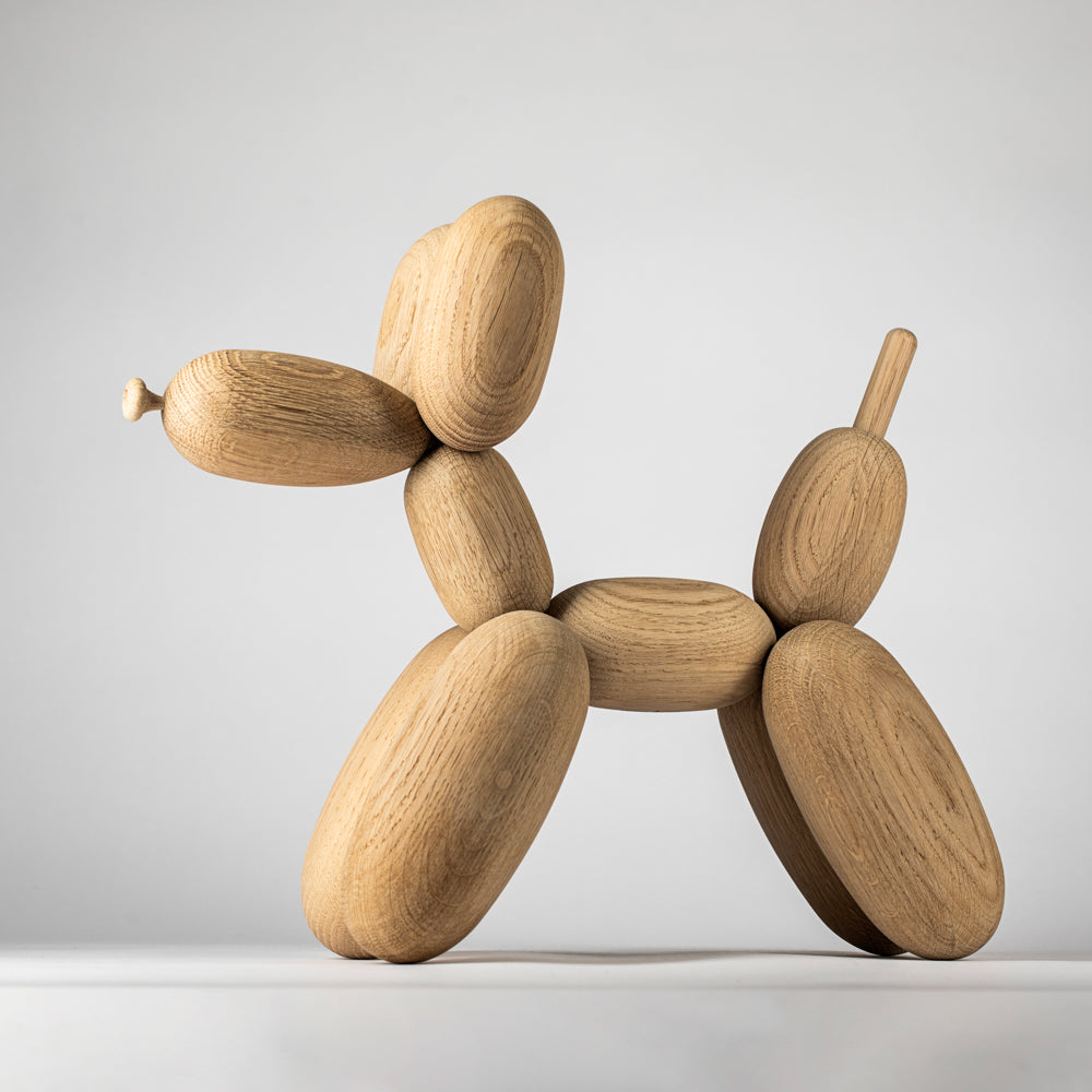 Wooden balloon dog sculpture on a light gray background