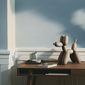 Decorative balloon dog sculpture on a wooden surface with a light blue wall in the background