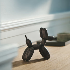 Wooden dog sculpture on a wooden surface with a blurred background