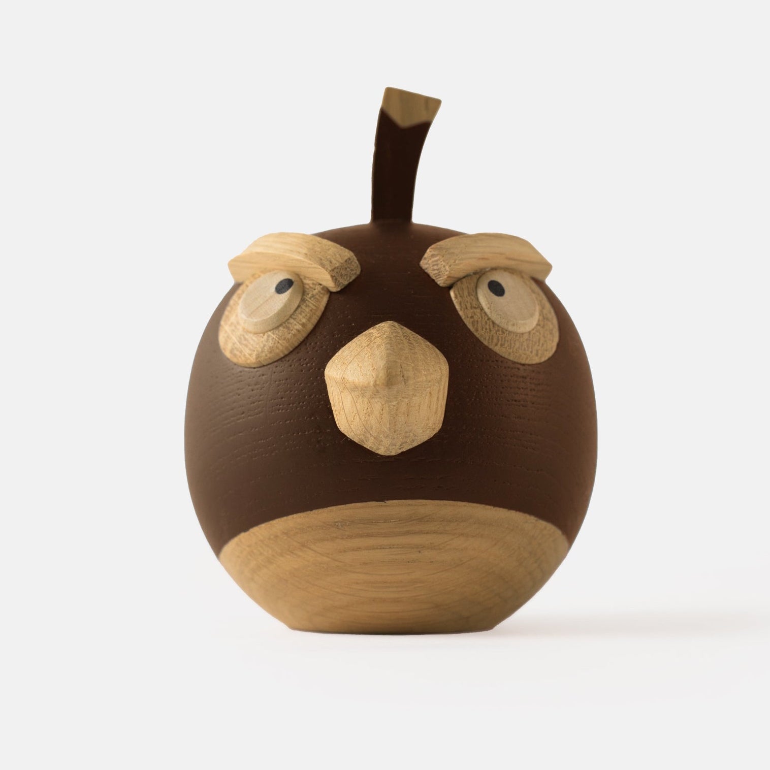 Wooden figurine of an animated cartoon bird character carved from dark and light wood, featuring a round body, prominent beak, expressive eye details, a small top stem, visible natural wood grain, and a smooth matte surface on a plain white background.