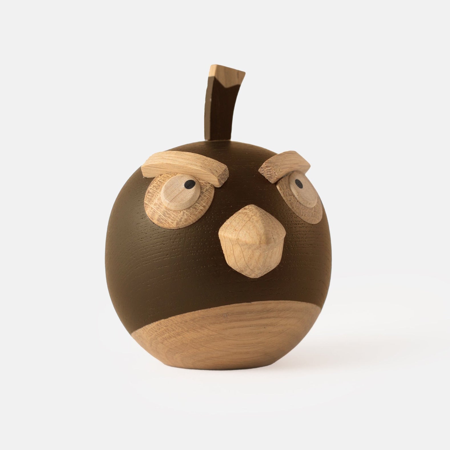 Wooden figurine of an animated cartoon bird character carved from dark and light wood, featuring a round body, prominent beak, expressive eye details, a small top stem, visible natural wood grain, and a smooth matte surface on a plain white background.