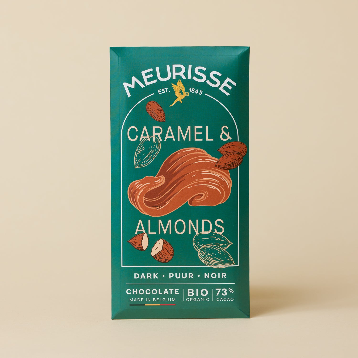 Meurisse dark chocolate bar with caramel and almonds, 73% organic cacao, in deep green packaging with illustrated caramel swirl and almond motifs, standing upright against a light beige background.