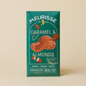 Meurisse dark chocolate bar with caramel and almonds, 73% organic cacao, in deep green packaging with illustrated caramel swirl and almond motifs, standing upright against a light beige background.