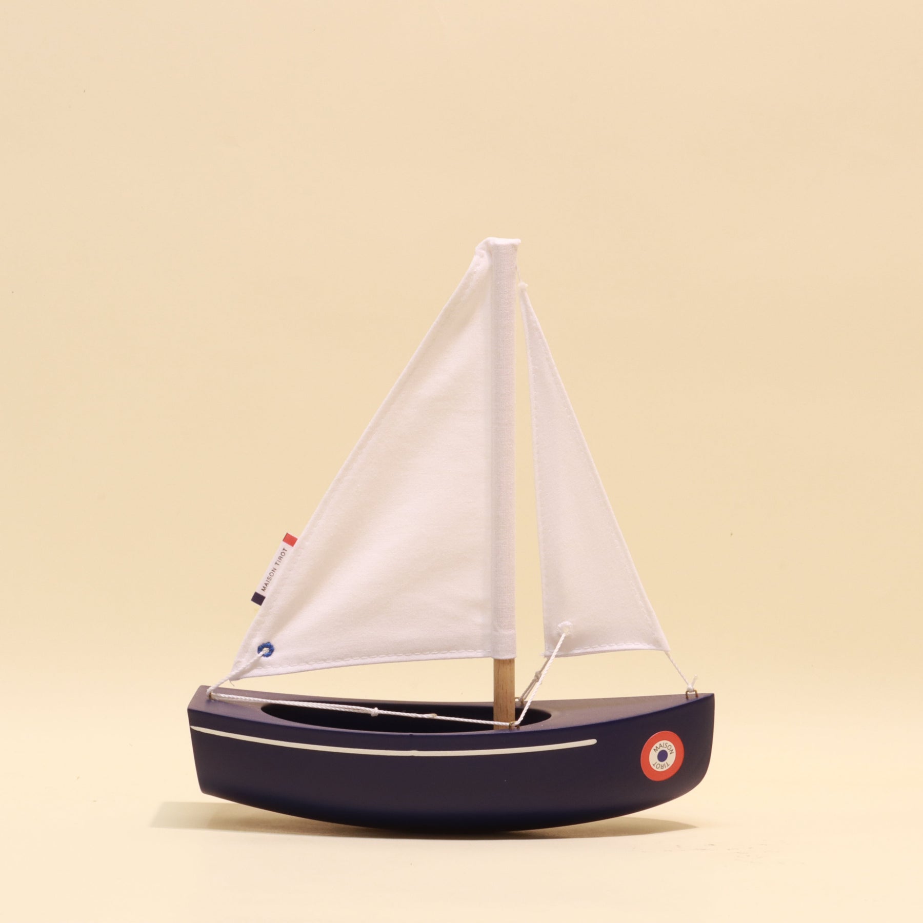Model sailboat with white sail on a beige background