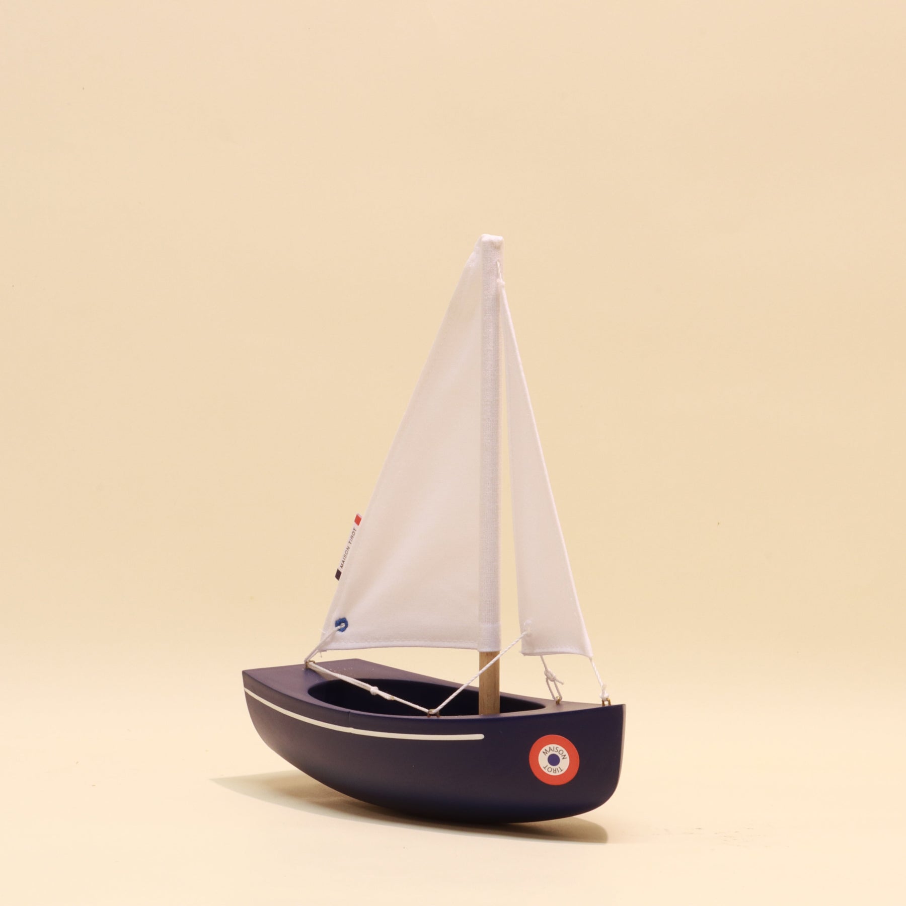 Model sailboat with white sails on a beige background