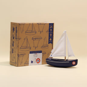 Model sailboat in front of its packaging box on a beige background