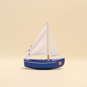 Model sailboat with a white sail on a beige background