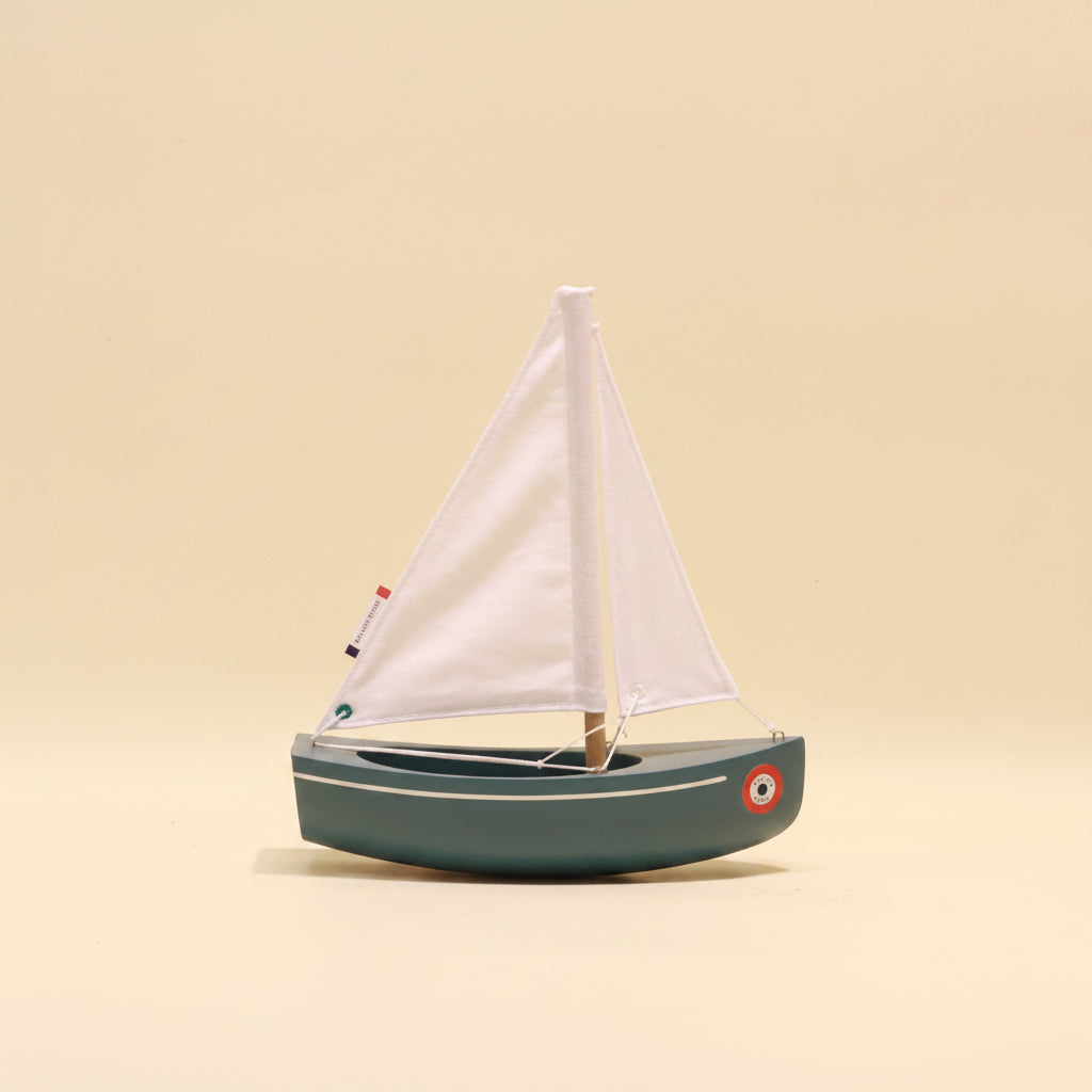 Model sailboat with white sail on a beige background