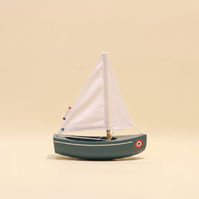 Model sailboat with white sail on a beige background
