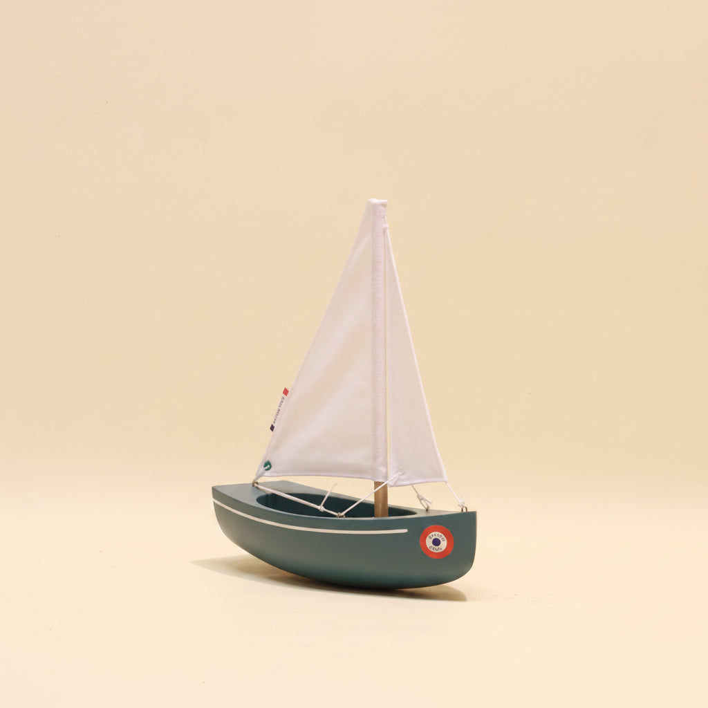 Model sailboat with white sail on a beige background