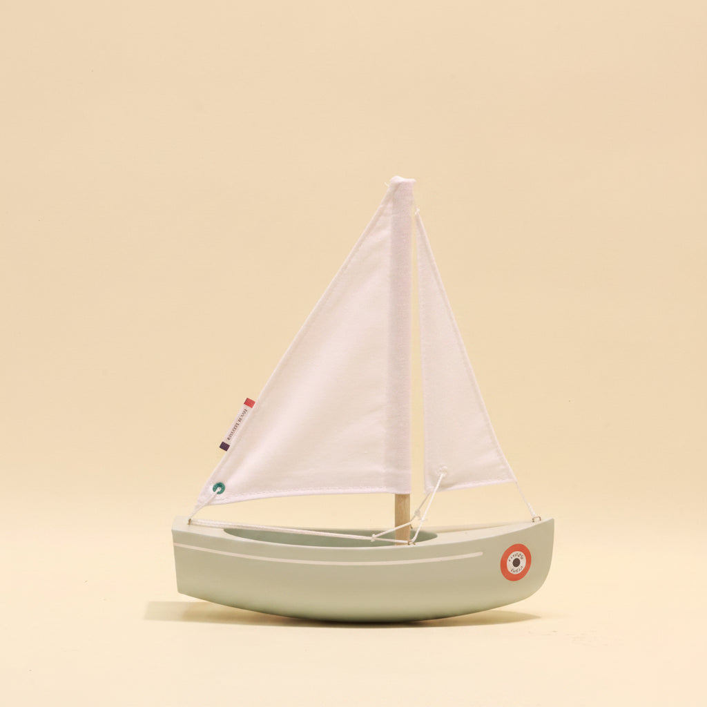 Model sailboat with white sail on a beige background