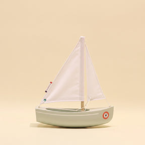 Model sailboat with white sail on a beige background