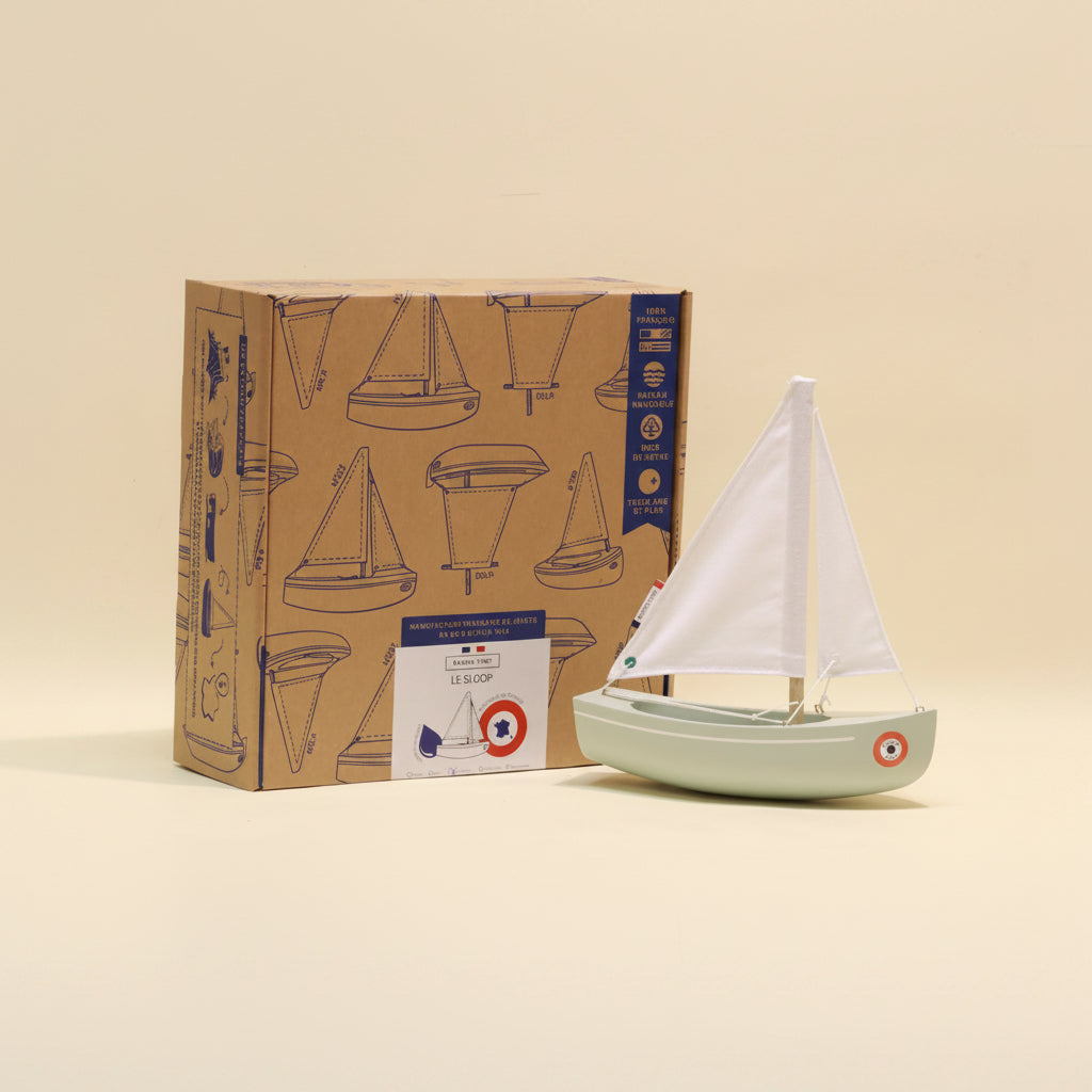 Model sailboat in front of a box with sailboat design