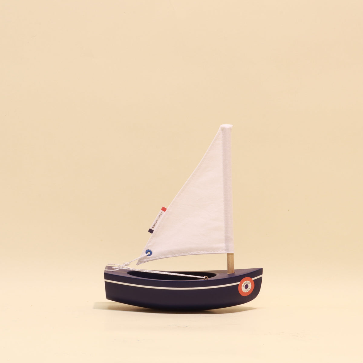 Model sailboat with a white sail on a beige background