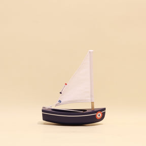 Model sailboat with a white sail on a beige background