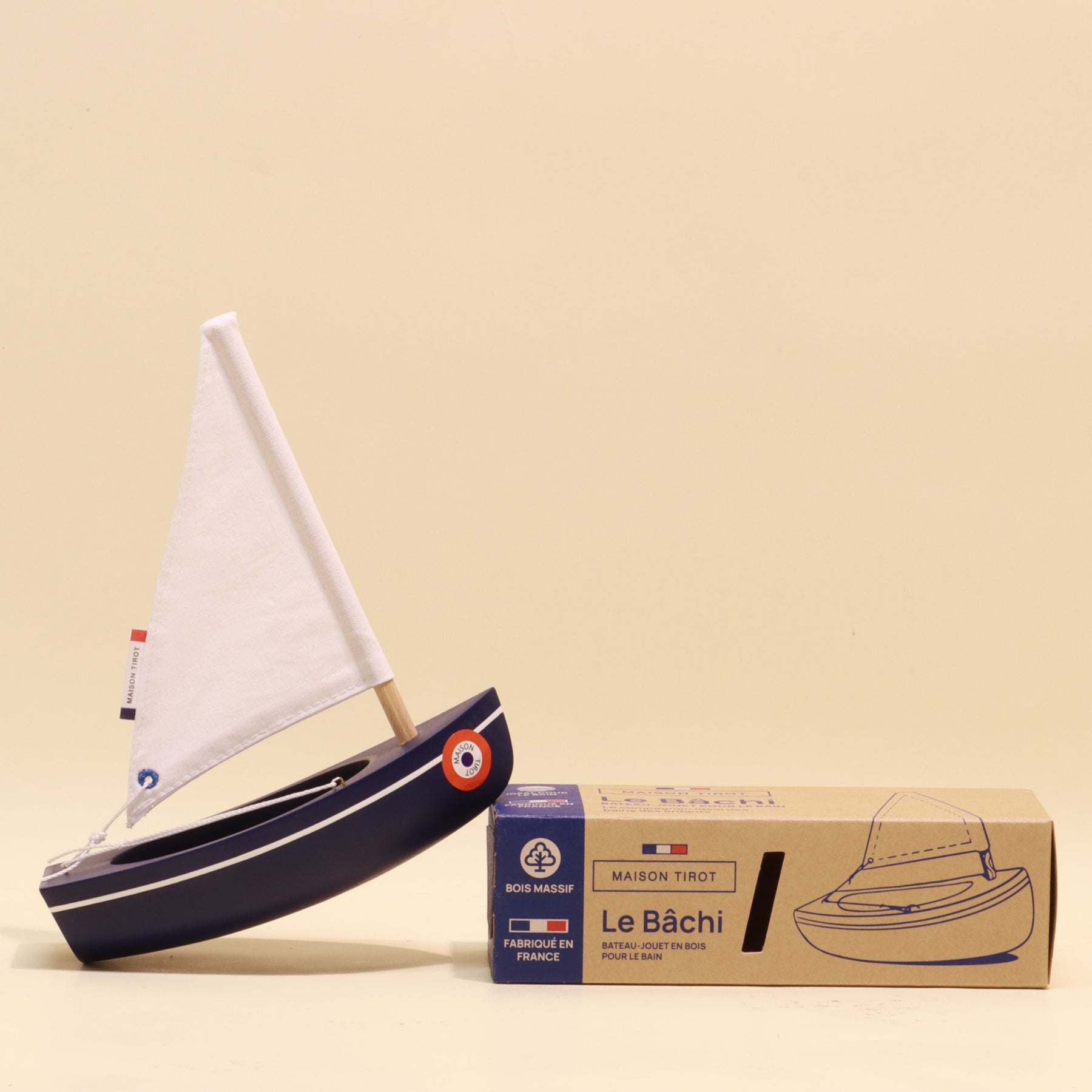 Model sailboat with a box labeled 'Le Béchi' on a beige background