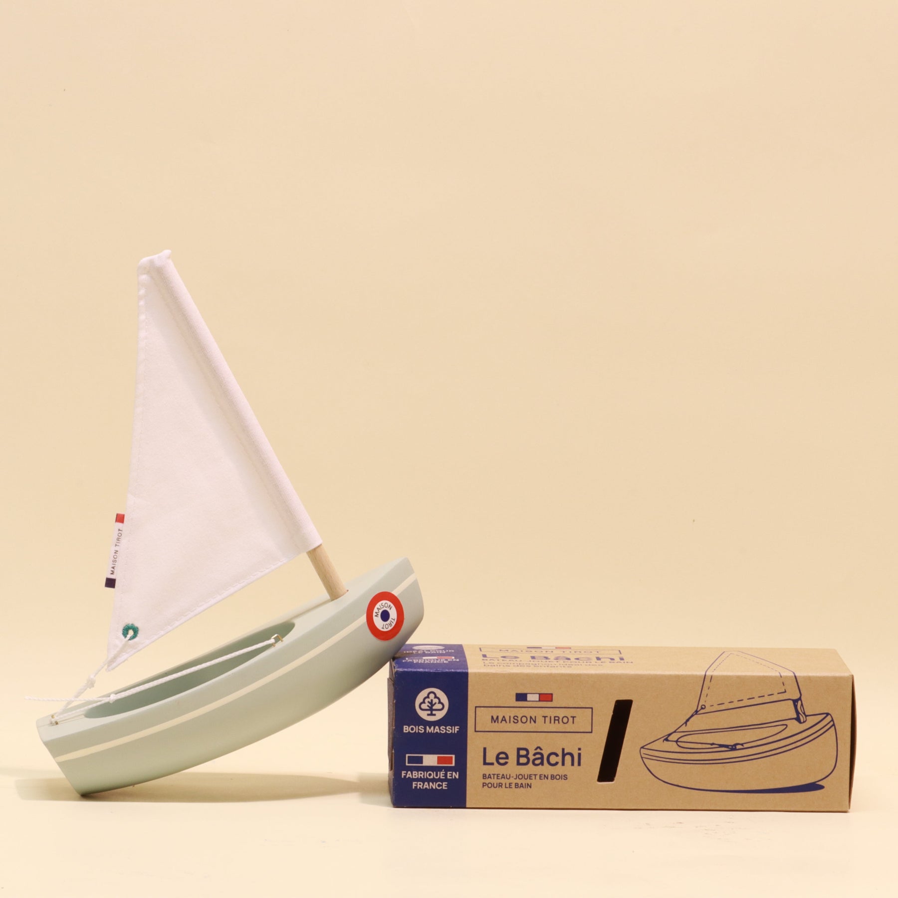 Model sailboat with a cardboard box on a beige background