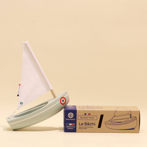 Model sailboat with a cardboard box on a beige background