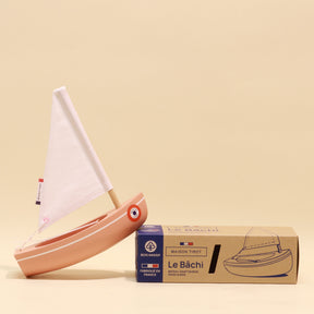 Model sailboat with a cardboard packaging box on a beige background