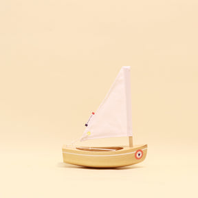 Small wooden sailboat model on a beige background