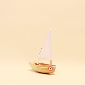 Small wooden sailboat model on a beige background