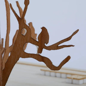 Wooden cutout of a tree with a bird on a plain background