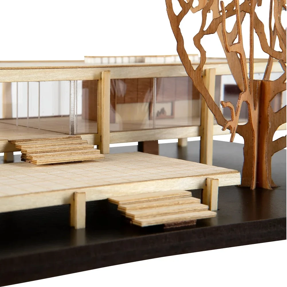 Wooden model of a bridge with steps and a decorative tree-like structure on a dark surface.